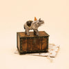 The Elephant Cake Topper - Final Sale (ships in one week) features a hand-painted elephant with a party hat, standing on a vintage wooden box atop a star-patterned fabric pouch—a charming collectible keepsake.
