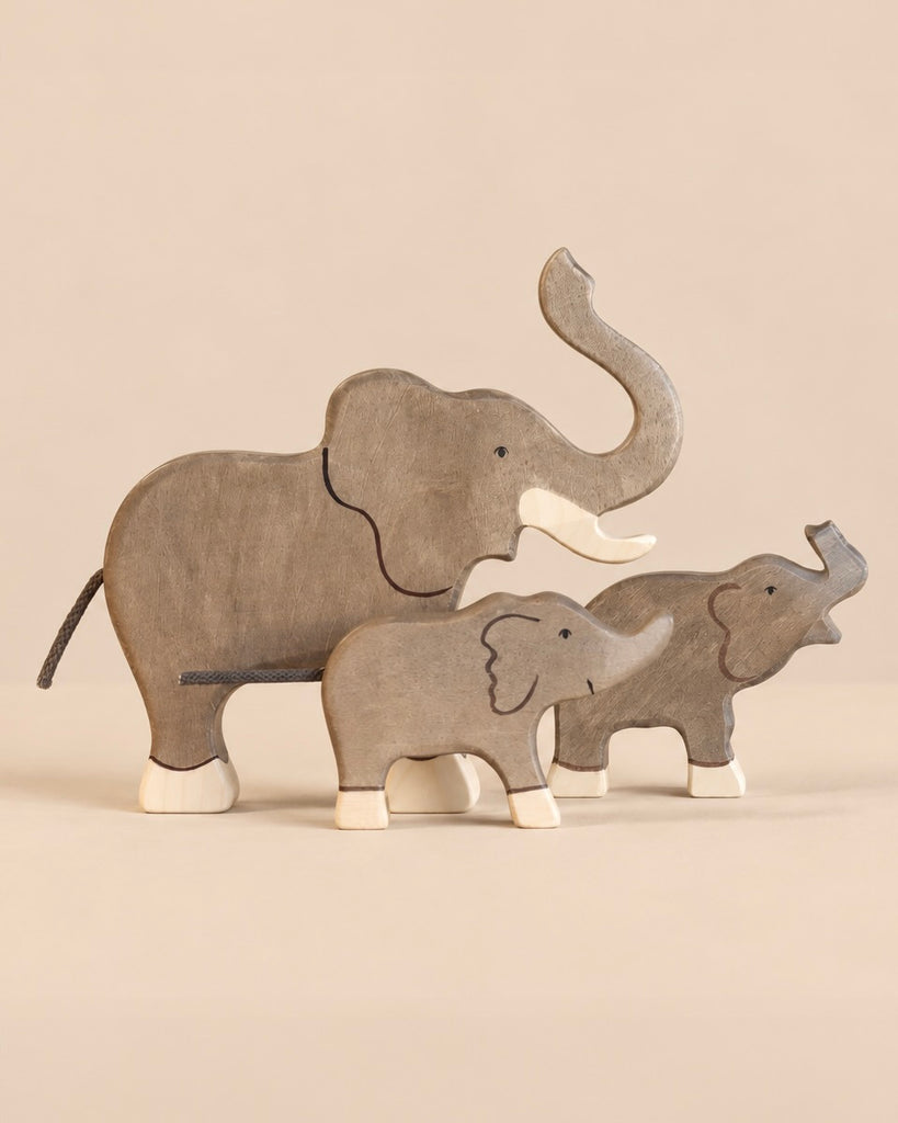 Holztiger Handmade Wooden Elephant Family Set consisting of three handcrafted wooden elephant figures of varying sizes, each with light-colored feet.