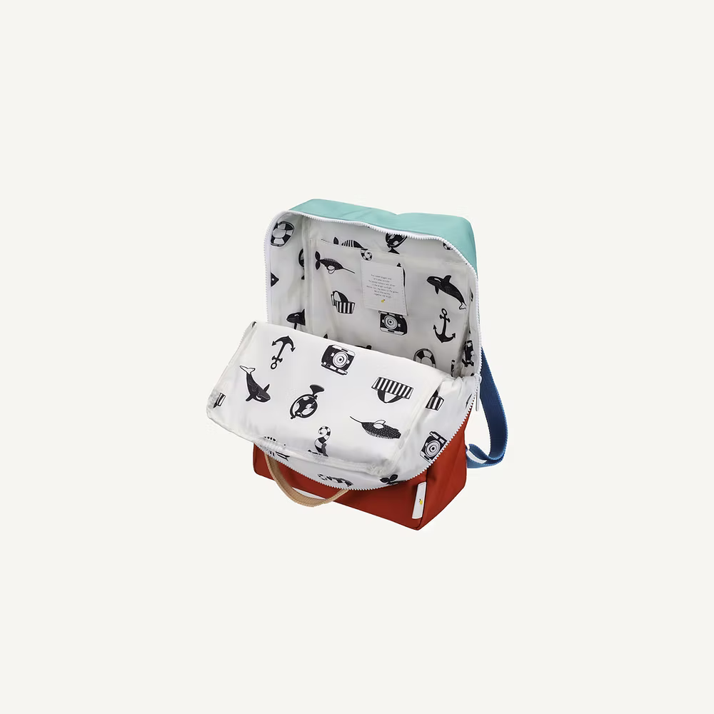 The Sticky Lemon Backpack Large | Color Blocking | Aquatic Green + Shipwreck Rust features a colorful design with an open flap, a white interior decorated with black nautical prints, plus a waterproof lining and recycled PET materials for durability.