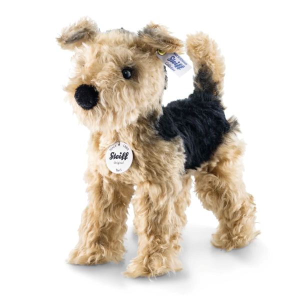 The Steiff Mohair Terri Welsh Terrier is a 10-inch plush dog with curly tan and black mohair fur, button eyes, a black nose, a Steiff ear tag, and a round white Steiff chest tag.