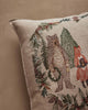 A Coral & Tusk Christmas Cheer Wreath Pillow featuring a linen cover embroidered with a bear and a fox standing within a holiday wreath of pine branches, berries, and mistletoe.