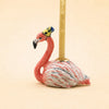 The Flamingo Cake Topper - Final Sale (ships in one week) features a ceramic flamingo with a yellow and blue party hat holding a tall candle—perfect as a unique handcrafted keepsake or collectible birthday gift.