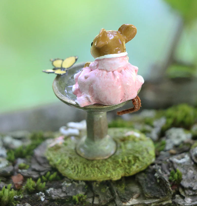 The Wee Forest Folk Tiny Collectible - Garden Spa (Not a Toy) features a hand-sculpted mouse in a pink dress on a birdbath, watching a yellow butterfly, set on mossy bark with a charming soft green background.