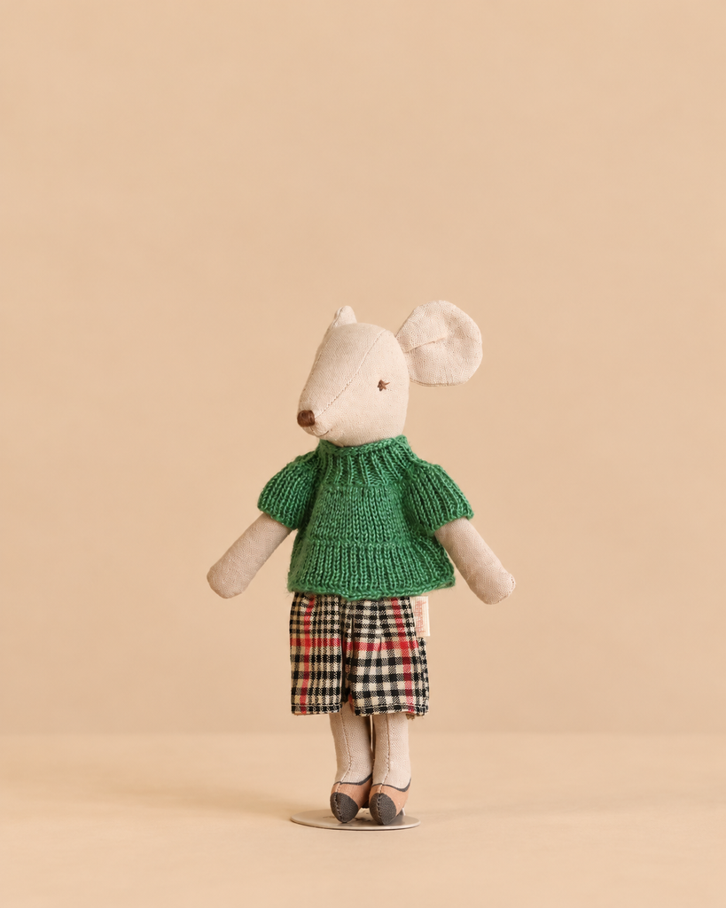 A Maileg mouse doll from the Maileg Grandma’s Living Room Set, wearing a green sweater and a plaid skirt.