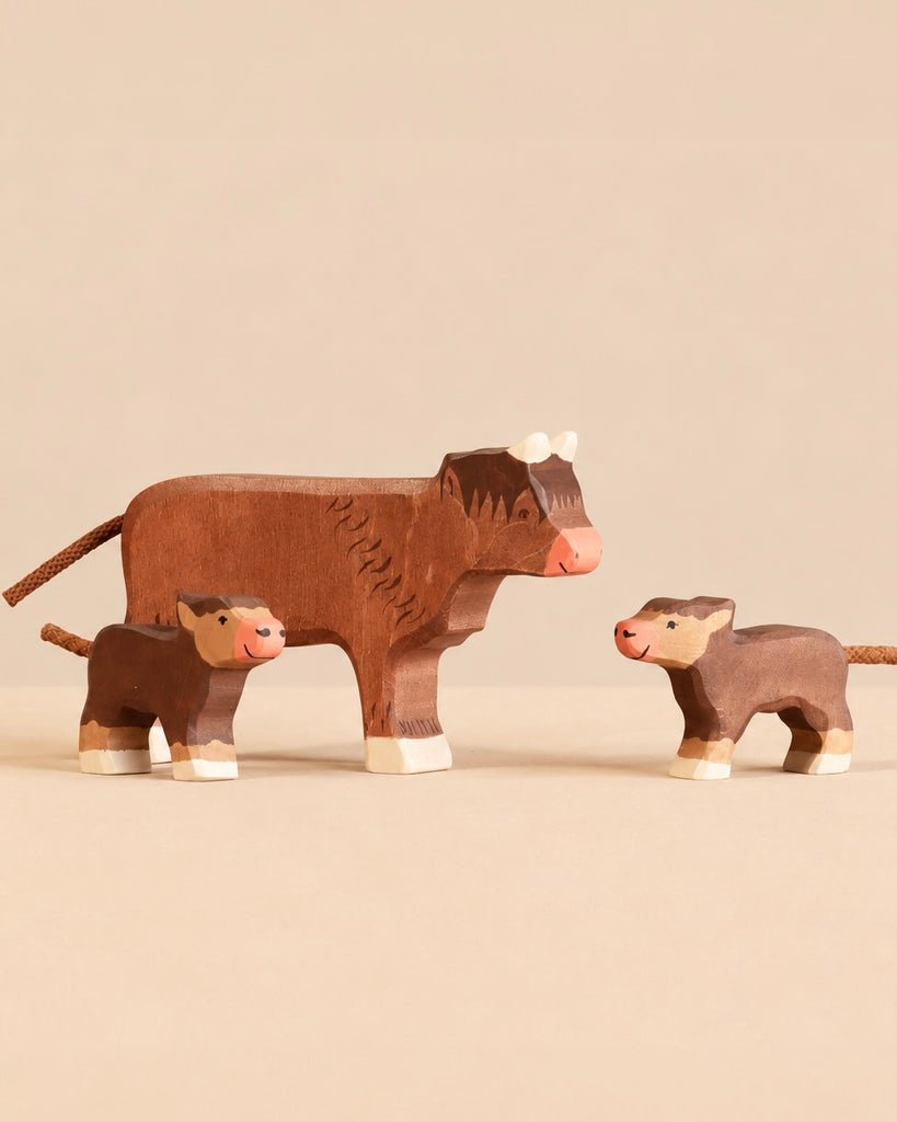 Holztiger Handmade Wooden Highland Cow Family Set featuring a handcrafted wooden Highland cow figure standing with two smaller calves, perfect for open-ended play.