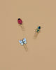 The Curio Enamel Paper Clip Set features three clips—a red ladybug, yellow and black beetle, and light blue butterfly—arranged on a beige background. Each measures about 4 x 4 x 0.5 in (10.2 x 10.2 x 1.3 cm).
