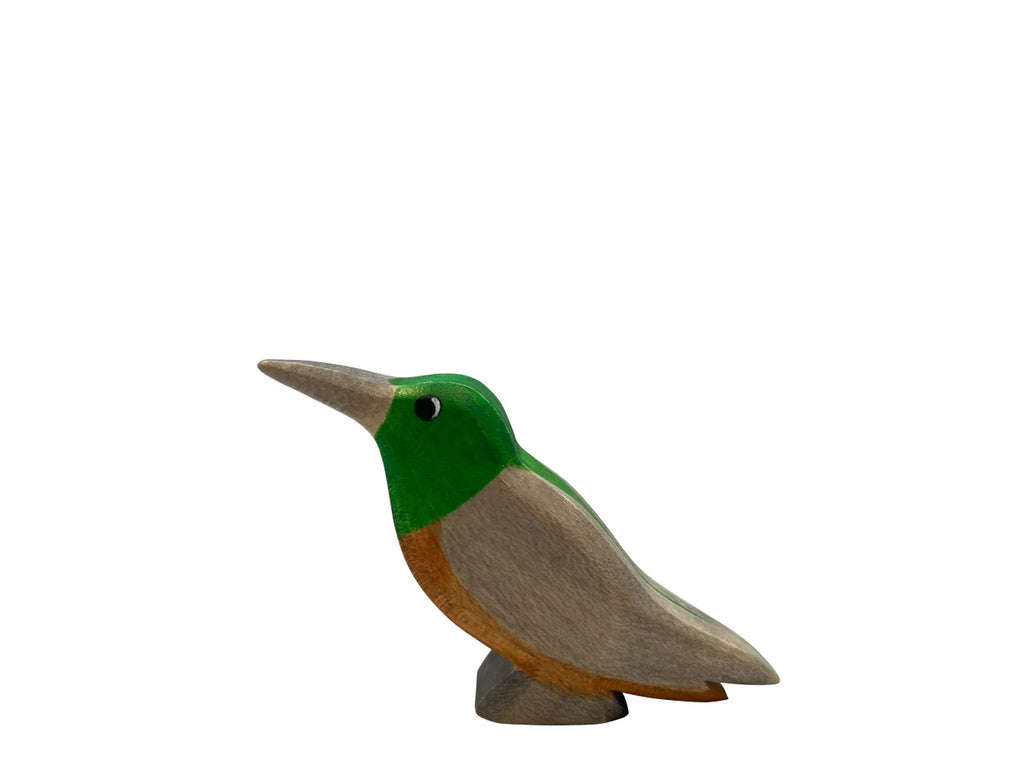 A Handmade Holzwald Kolibri Bird sculpture, painted in green and beige, displayed against a plain white background, representing sustainable toys.