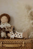 The Handmade Wooden Mini Lamp - Puppy, featuring heart-shaped cutouts, is a charming decorative piece perfect for nursery decor—ideal displayed on a basket beside cuddly toys with soft beige pampas grass in the background.