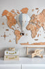 A decorative wooden world map hangs on the wall behind the Hot Air Balloon - Beige / Mint / Grey model. Below, a white dresser displays stacked suitcases and a wooden toy airplane, creating a charming children's room decor.