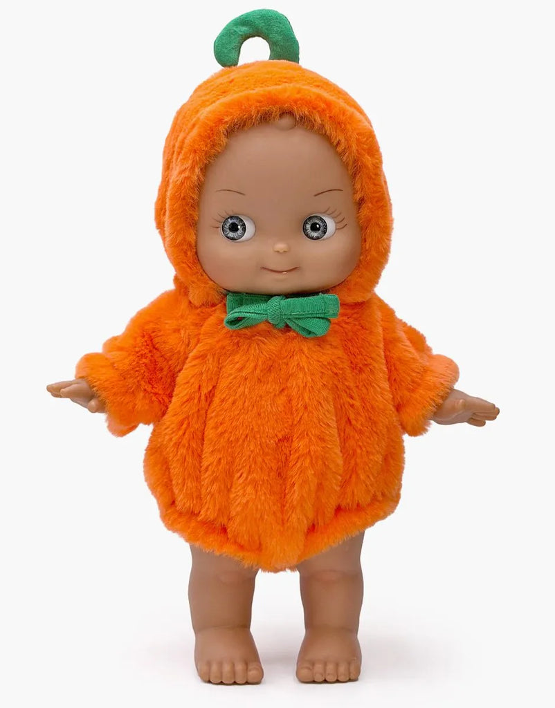 Minikane Mini Pancha Doll - Maia Celebrating with Pumpkin Halloween Outfit wearing a fuzzy orange pumpkin costume with a green stem hood and a green bow tie, perfect for imaginative play.