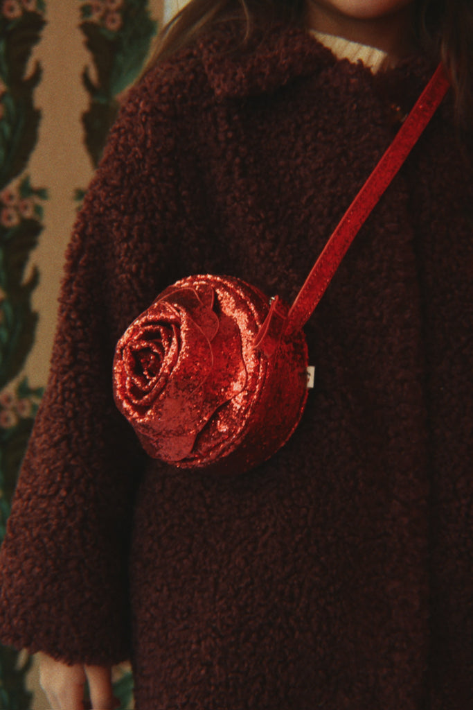 A round, glittery red Konges Sloejd Rose Shoulder Bag with a slim shoulder strap and zipper closure.