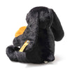 The Steiff Mr. Spice Hoppie Rabbit is a soft black plush with long floppy ears, sitting facing away while holding an orange heart. It features a fuzzy surface and has the signature yellow Steiff Button in Ear tag attached.