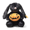 Steiff Mr. Spice Hoppie Rabbit is a plush black Halloween bunny holding a soft orange jack-o'-lantern pumpkin. It sits upright with a white nose, velvety fur, and features the signature Steiff Button in Ear.