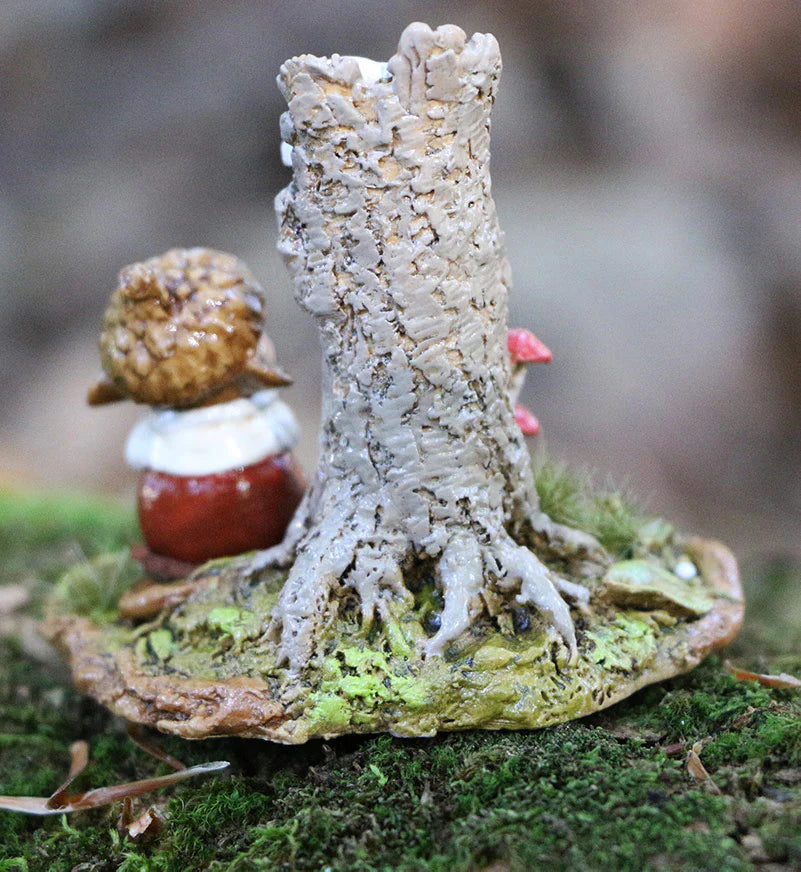 The Wee Forest Folk Tiny Collectible - My Happy Place (Not a Toy) features a tree stump with exposed roots on mossy ground, with a gnome-like figure in a brown hat and red coat peeking out from behind the stump.