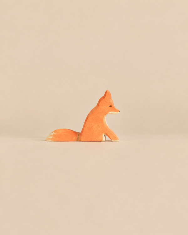 An Ostheimer Fox - Sitting, a handcrafted wooden toy fox in a sitting position, painted in shades of orange and white.