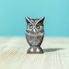The Bumbu Handmade Wooden Ancient Oak Tree with Owl Set features a small painted owl with yellow eyes, crafted from sustainable maple wood, standing on a light wooden surface against a solid light blue background.