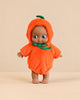 A Minikane Mini Pancha Doll - Maia Celebrating with Pumpkin Halloween Outfit wearing a fuzzy, hooded orange pumpkin costume with a green stem on top.