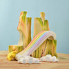 The Bumbu Wooden Rainbow Cliff, crafted from sustainably sourced wood, features pastel cliffs, a curving rainbow with clouds, and a yellow sun on a pale blue background—perfect for imaginative play. Ships in one week.