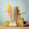 The Bumbu Wooden Rainbow Cliff (ships in one week) is crafted from sustainably sourced wood, featuring pastel waterfalls, clouds, a yellow sun, green cliffs, and white branches—perfect for imaginative play.