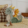 A Handmade Wooden Lamp - Dragon, Hunter Green sits on a checkered bedspread beside a plush toy and a brown-and-white checkered pillow, adding charming nursery decor to this cozy bedroom setting.