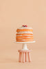 A stack of pancakes topped with berries sits on a white cake stand with a beaded edge, placed on the Maileg Stool Set, Mouse in Mint/Light Yellow, which features a vintage paint finish against a beige background.