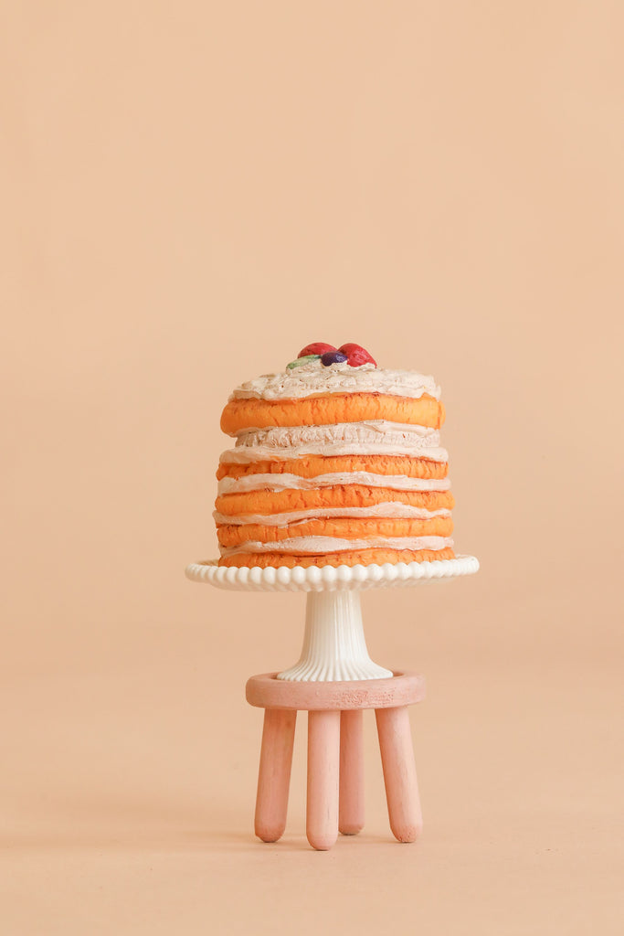 A stack of pancakes topped with berries sits on a white cake stand with a beaded edge, placed on the Maileg Stool Set, Mouse in Mint/Light Yellow, which features a vintage paint finish against a beige background.
