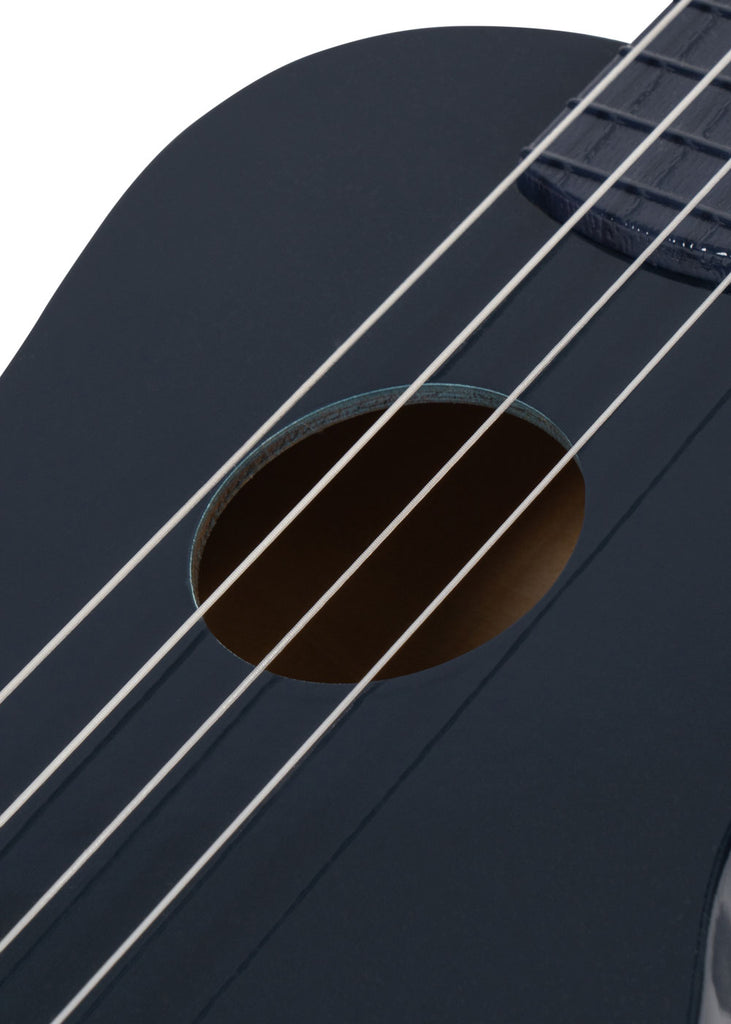 Close-up of the Konges Sloejd Wooden Ukulele - Midnight, featuring FSC-certified dark blue wood, sound hole, and four strings, set against a white background.