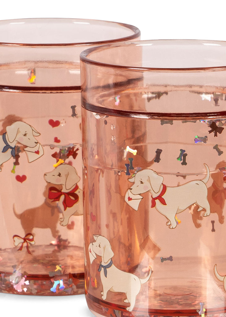 The Konges Sloejd Glitter Cup - Woof Letter Rose features a playful design with white dogs in red bows carrying envelopes, surrounded by colorful bones and hearts—a whimsical kids cup perfect for any occasion.