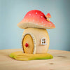 The Bumbu Wooden Toadstool House is a small, whimsical yellow mushroom-shaped playset with a red, white-spotted cap roof. Handcrafted from wood, it features a round door with a red diamond and a tiny window.