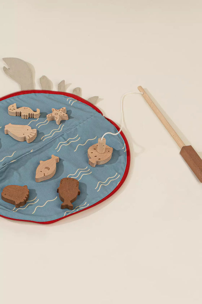 The Wooden Fishing Game with Bag features a blue fabric mat with white wavy lines, wooden animal shapes, and a fishing rod with string—perfect for sparking cognitive growth and imaginative fishing adventures.