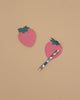 Two Strawberry Sticky Notes, pink with green tops and a fun die-cut strawberry shape, rest on a beige surface. A multicolored pen is placed diagonally across one of the adhesive sheets.
