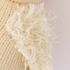 Close-up view of a Cuddle + Kind Baby Duckling hand-knit fabric with frayed edges and visible fluffy threads, highlighting its texture.