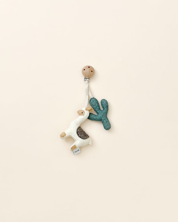 A handmade Llama Pram Clip with a wooden clasp, featuring soft wool llama and cactus charms, set against a plain beige background.