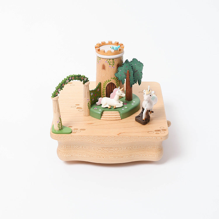 The Unicorn Music Box features a hand-cranked design with a castle tower, white unicorns, trees, and decorative columns on a light wood base—a charming Wooderful Life collectible.