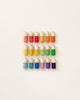 Four rows of colorful, wooden egg-shaped Grapat Buds/Brots toys, arranged neatly on a pale background. Each row contains eggs with the same colored horizontal stripes.
