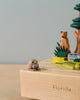 A Florida Wooden Music Box featuring a small, carved manatee in the foreground and a bear by a tree in the background, set against a neutral background.