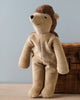 A Senger Naturwelt stuffed animal hedgehog wearing a zip-up onesie made from organically grown cotton with a hood shaped like a monkey's head, sitting against a wicker basket on a plain background.