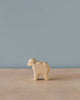 A Handmade Holzwald Lamb Standing figurine, displayed on a wooden table against a pale blue background. The lamb is simplistic in design with visible wood grain, epitomizing the charm of sustainable toys.