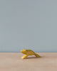 A Handmade Holzwald Jumping Frog, painted yellow, positioned on a flat surface against a plain light grey background, from the Holzwald Brand.