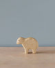 A simple Handmade Holzwald Sheep stands on a plain surface against a light blue background. The toy has minimalist features and is made from sustainable wood, presenting a soft natural finish.
