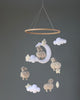 A handmade baby nursery mobile featuring Little Sheep, clouds, and a moon, hanging from a circular wooden frame against a neutral background.