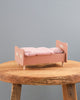 A small pink Wooden Bed for Teddy Mum - Rose with plaid bedding and handpainted details on it, labeled "Teddy" and decorated with white snowflakes, placed centrally on a rustic wooden table against a plain