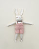 A Polka Dot Club Cream Rabbit in Hand Knit Overalls toy with white and pink features, lying flat against a neutral background.