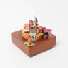 wooden music box with a town in the middle and red train going around it